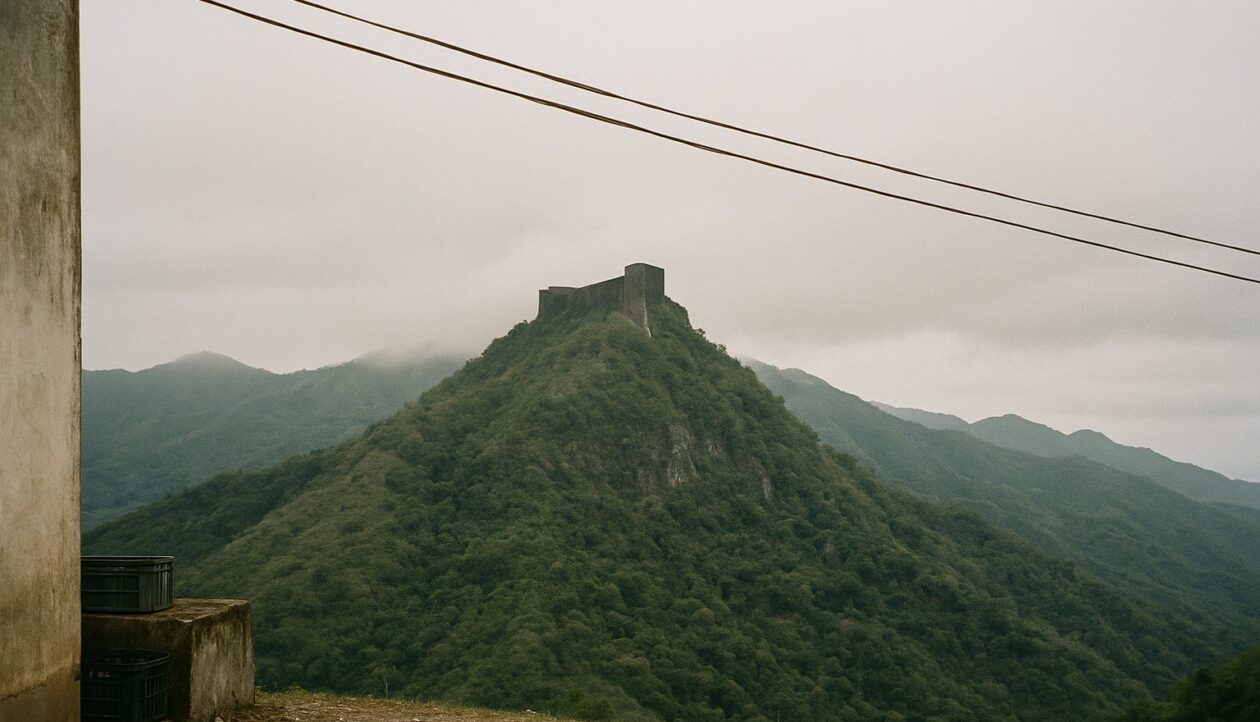 Die Citadelle Laferrière auf einem kahlen Berggipfel, ringsum bewaldete Bergrücken unter tiefer Wolke.